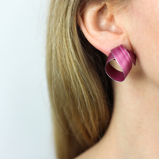 Pink wide coil stud earrings worn